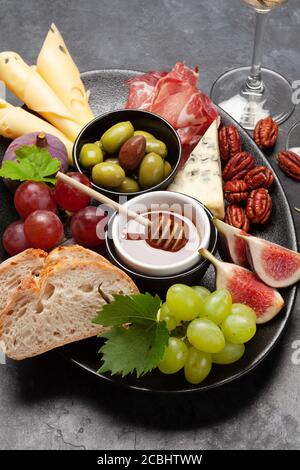 Assiette d'antipasti avec prosciutto, fromage, figues et raisins. Hors-d'œuvre et vin blanc Banque D'Images