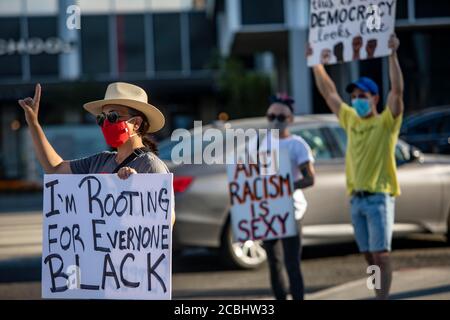 Los Angeles, Californie, États-Unis. 12 août 2020. Mara Casey (à gauche) donne un signe de paix aux voitures qui passent alors qu'elle proteste en faveur de Black Lives à l'extérieur de la Galleria à Sherman Oaks dans le cadre du groupe Valley of change. Le groupe proteste tous les jours de la semaine depuis mai 31. Credit: Jill Connelly/ZUMA Wire/Alay Live News Banque D'Images