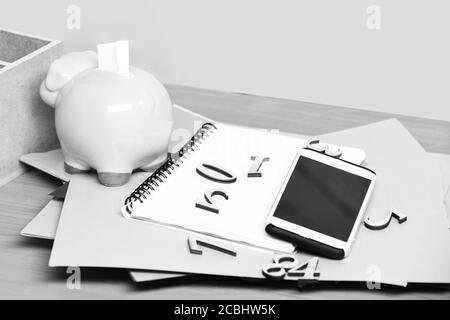 différents papiers avec numéros, copybook, porcins roses banque et téléphone cellulaire, sur table en bois marron Banque D'Images