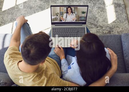 Consultation médicale en ligne avec un médecin. Femme médecin thérapeute et psychologue sur un écran d'ordinateur portable communique avec un couple en utilisant le chat vidéo. Banque D'Images