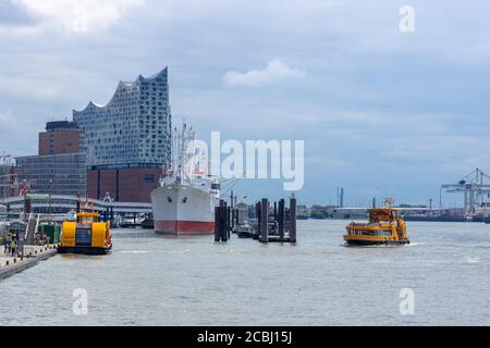 Hambourg, Allemagne - 8 juin 2020 : salle philharmonique d'Elbe dans la ville de hafen, au bord de l'elbe. Un ferry traverse la rivière à l'avant. Banque D'Images