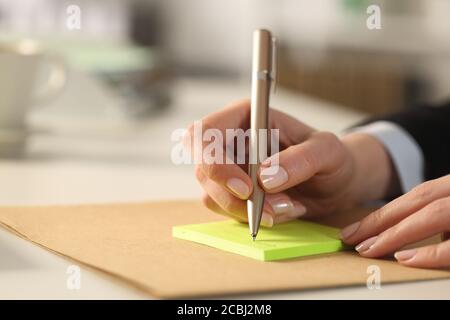 Gros plan d'une femme dirigeante écrit des mains sur collantes bloc-notes sur un bureau au bureau Banque D'Images