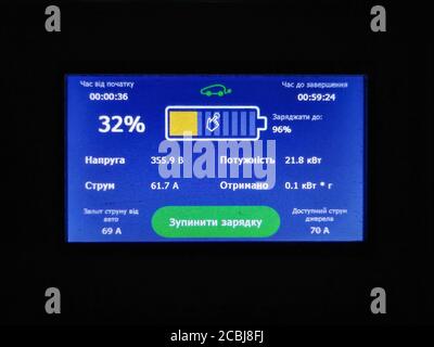 Écran bleu avec tableau de charge de la batterie. Faire le plein de voiture électrique à la station-service la nuit. Piste Kiev-Odessa. Concept d'énergie verte. Gros plan. Août Banque D'Images