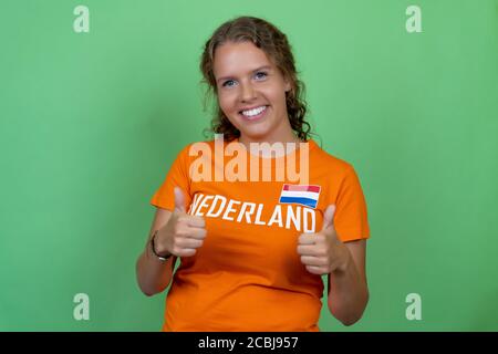 Bonne blonde femme fan de football des pays-Bas isolé sur le vert arrière-plan Banque D'Images