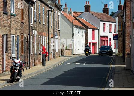 Postier livrant du courrier dans le village de Cawood, dans le North Yorkshire, en Angleterre Banque D'Images