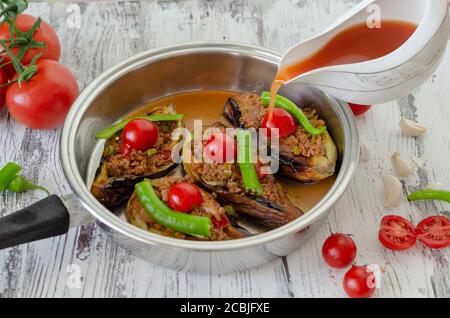 La femme verse de la sauce tomate dans la casserole pour cuisson des plats d'aubergines Banque D'Images