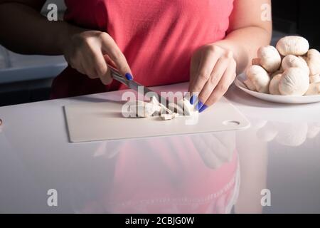 des champignons champignons coupés à la main sur un plateau en plastique blanc sur une table blanche. processus de cuisson. Photo de haute qualité Banque D'Images