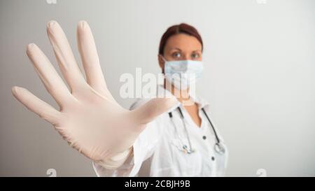 Une femme avec un masque médical blanc et un gant en latex montre le symbole STOP. Arrêter la maladie. Prévention des virus. Espace négatif ou espace de copie Banque D'Images
