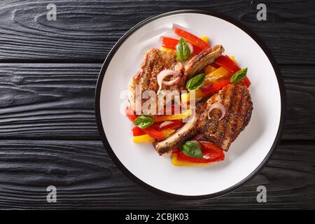 Délicieux côtelettes de porc grillées avec poivrons, oignons et basilic dans une assiette sur la table. Vue horizontale du dessus Banque D'Images