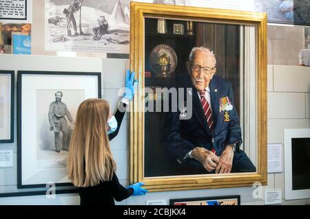 Un membre du personnel ajuste un portrait du capitaine Sir Tom Moore par l'artiste Alex Chamberlin, tel qu'il est dévoilé au Musée national de l'Armée à Chelsea, Londres, pour souligner le 75e anniversaire de la journée VJ. Banque D'Images