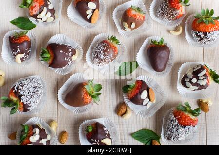 Variété de fraises recouvertes de lait, de chocolat noir et blanc et de noix Banque D'Images