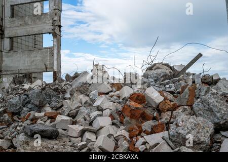 Débris de béton avec barre d'armature sur le fond d'un bâtiment détruit et d'un ciel gris. Arrière-plan. Banque D'Images