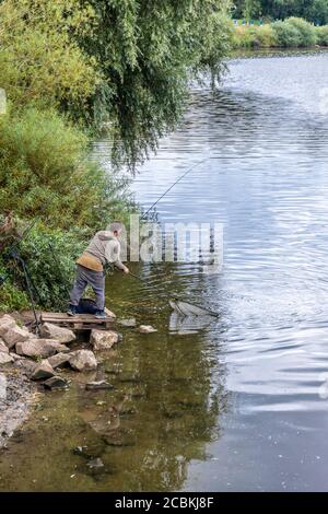 Un pêcheur à la ligne utilisant un filet d'atterrissage pour amener une anguille capturée dans la rivière Severn à Wainlode, Gloucestershire Royaume-Uni Banque D'Images