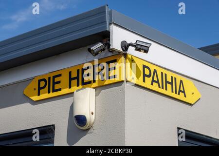 Panneau amusant sur un mur de restaurant dans la ville côtière de Paihia, Île du Nord, Nouvelle-Zélande. Tarte ici / Paihia. Banque D'Images