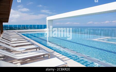 Chaises longues près de la piscine moderne à débordement Banque D'Images