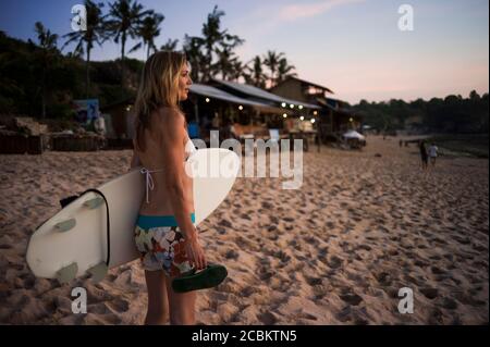 Femme tenant une planche de surf, regardant la mer, Balangan, Bali, Indonésie Banque D'Images