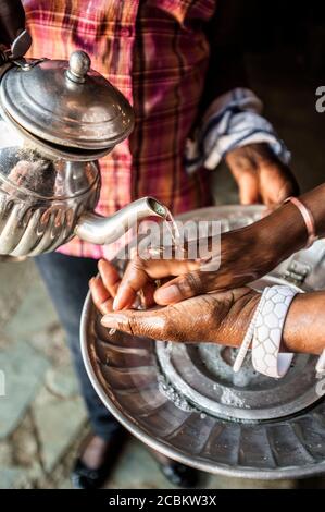 Gros plan du serveur versant de l'eau sur les mains des mans dans le restaurant, Katutura, Namibie, Namibie Banque D'Images