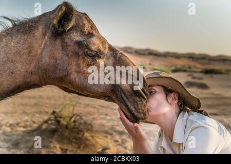 Jeune femme embrassant chameau, Abu Dhabi, eau Banque D'Images