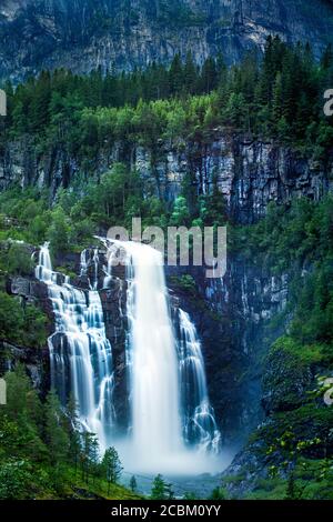 La cascade de Skjervsfossen est entourée de pins et d'immenses falaises, près de Voss, en Norvège Banque D'Images