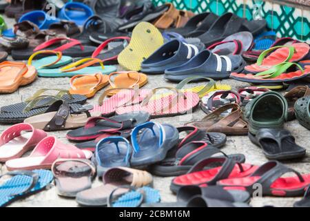 Des rangées de chaussures et des tongs sur le trottoir à l'extérieur de la mosquée, Malacca, Malaisie Banque D'Images