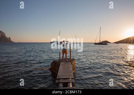 Jeune homme debout sur la vieille jetée au coucher du soleil, Ibiza, Espagne Banque D'Images