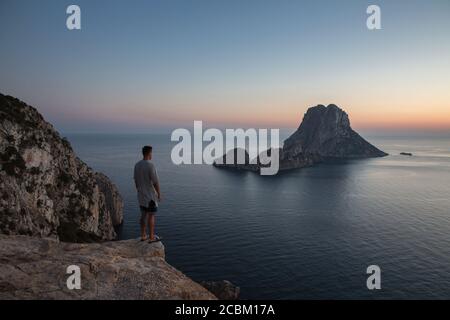Jeune homme regardant le coucher du soleil sur es Vedra , Ibiza, Espagne Banque D'Images