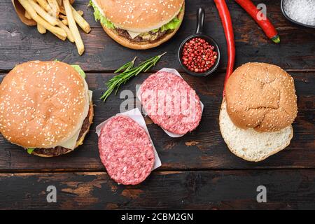 Bœuf haché hamburger steak côtelettes avec assaisonnement sur fond de bois foncé, topview Banque D'Images