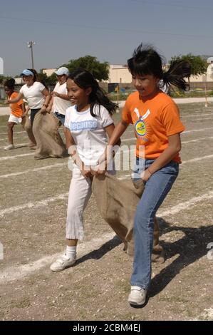 Austin Texas USA, mai 2006 : les filles de cinquième année participent à une course de sacs à trois pattes sur le terrain de jeu scolaire pendant la journée de piste et de terrain, qui marque traditionnellement la fin du semestre de printemps dans de nombreuses écoles primaires publiques de la région. ©Bob Daemmrich Banque D'Images