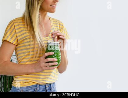Portrait court d'une femme souriante avec pot à smoothie aux légumes verts. Concept de régime de Detox. Copier l'espace Banque D'Images