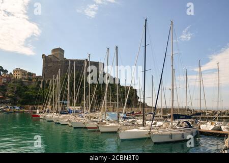 Vue sur le port avec des rangées de voiliers amarrés à la jetée et le village de pêcheurs avec le château médiéval en arrière-plan, Lerici, la Spezia, Italie Banque D'Images