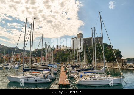 Vue sur le port avec des rangées de voiliers amarrés à la jetée et le village de pêcheurs avec le château médiéval en arrière-plan, Lerici, la Spezia, Italie Banque D'Images