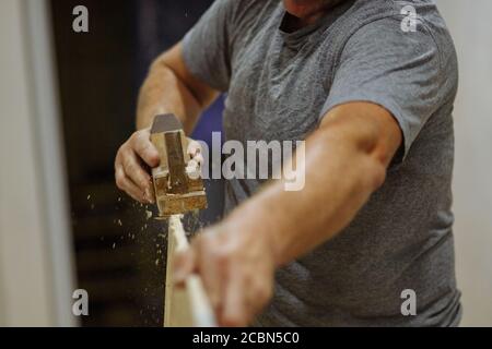 Les mains de l'homme meulent le panneau. Homme travaillant avec du bois. Réparation à domicile. Texture Banque D'Images