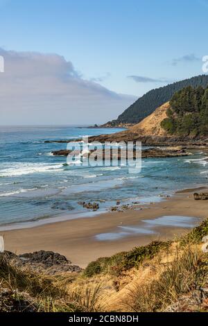 Vertical photo - UNE plage de sable et des collines accidentées le long de la côte de l'Oregon avec une banque de brouillard juste au large de la côte. Banque D'Images