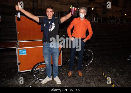 14 août 2020, Bade-Wurtemberg, Tübingen: Paul Wolff (l) se joint au maire de Lord Boris Palmer (Verts, r) pour célébrer sa bière gratuite, avec laquelle Palmer a annoncé l'utilisation de l'application d'avertissement Corona sur le marché du bois dans le centre-ville. Il a distribué un total de 300 bouteilles de bière à tous ceux qui avaient installé l'application Corona-WARN sur leur smartphone. Photo : Tom Weller/dpa Banque D'Images