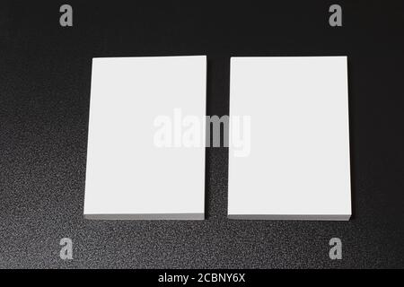 Deux livres avec une couverture vierge sur une table sombre et brillante, une série de maquettes modifiables prête pour votre conception, chemin de sélection inclus. Banque D'Images