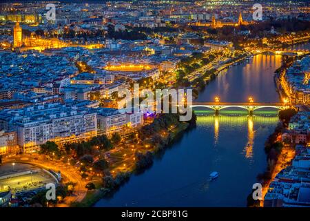 Vue aérienne du centre-ville de Séville la nuit, avec quelques-uns des principaux monuments : pont de Triana, rivière Guadalquivir, cathédrale, tour Giralda, Maestranza Banque D'Images