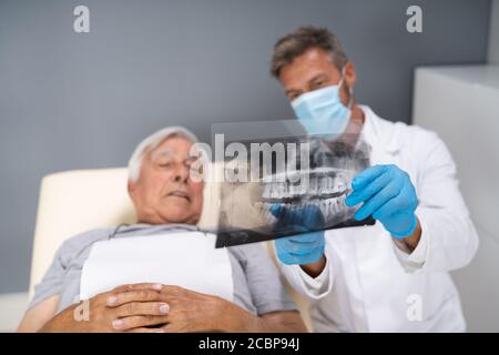 Dentiste examinant la radiographie dentaire de l'ancien senior Banque D'Images