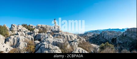 Jeune homme debout sur des rochers et regardant au loin, formations rocheuses calcaires, Réserve naturelle El Torcal, Torcal de Antequera, province de Banque D'Images