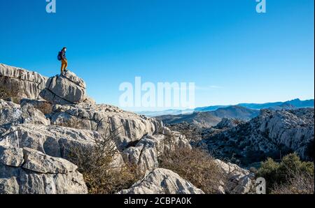 Jeune homme debout sur des rochers et regardant au loin, formations rocheuses calcaires, Réserve naturelle El Torcal, Torcal de Antequera, province de Banque D'Images