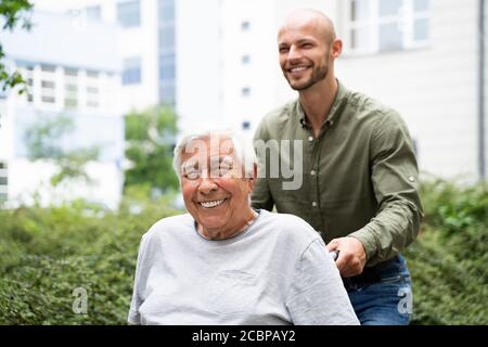Vieux souriant, transport en fauteuil roulant senior dans le parc Banque D'Images