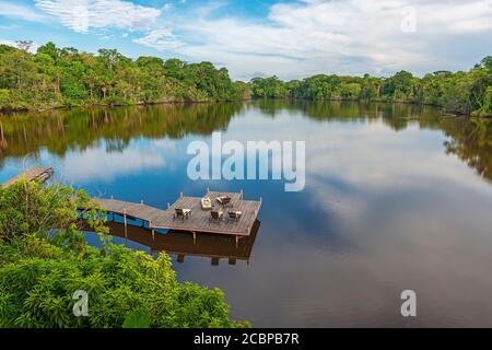 Les touristes se bronzer sur de longues chaises sur un quai dans un pavillon de la forêt amazonienne, en Équateur. Banque D'Images