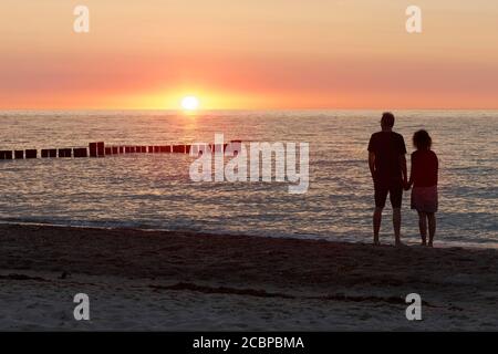 Couple tenant les mains, regardant le coucher du soleil sur la mer Baltique, Kuehlungsborn, Mecklembourg-Poméranie occidentale, Allemagne Banque D'Images