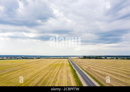 paysage aérien rural le jour d'été nuageux. route de campagne à travers les champs de blé Banque D'Images