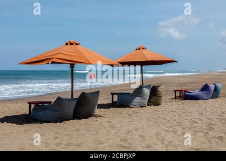 Parasols orange et sacs de haricots vides sur la plage de Berawa (Pantai Berawa), Canggu, Badung, Bali, Indonésie Banque D'Images