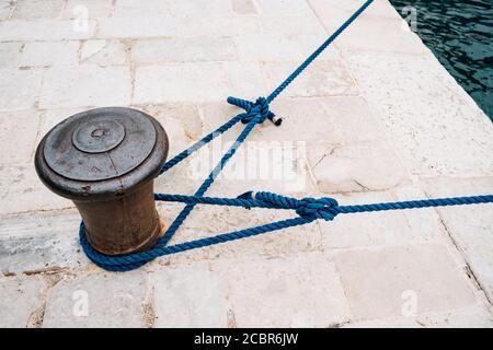 Le vieux métal maritime bollard avec des cordes d'amarrage. Banque D'Images