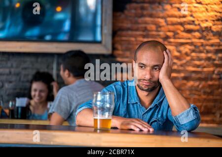 Un triste latin solitaire assis dans un bar ou un pub tout en buvant de la bière. Banque D'Images