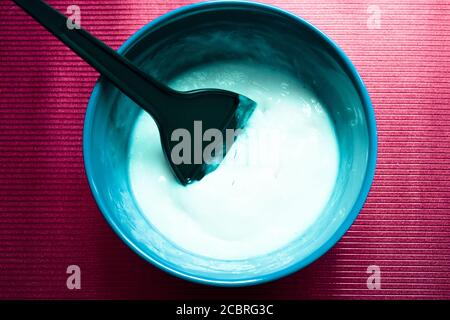 Bol bleu avec mélange pour teindre les cheveux. Palette de colorants à l'intérieur du bol mélangeur Banque D'Images