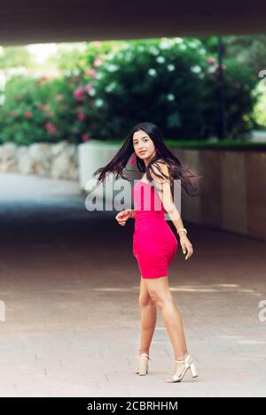 Jeune brunette Latina à cheveux longs, debout dans une longue robe donnant un voile sur elle-même avec les cheveux soufflant dans le vent. Mode concept Banque D'Images