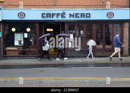 Les amateurs de shopping se promeuvent devant Caffè Nero sous la pluie à Sevenoaks Kent Banque D'Images