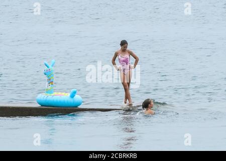 Lyme Regis, Dorset, Royaume-Uni. 15 août 2020. Météo Royaume-Uni. Nageurs à la station balnéaire de Lyme Regis à Dorset sur une chaude après-midi nuageux. Crédit photo : Graham Hunt/Alamy Live News Banque D'Images